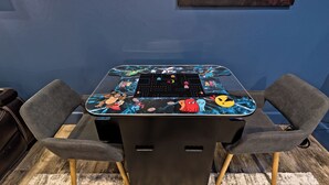 A table with a colorful design, two grey chairs, and a black cabinet.