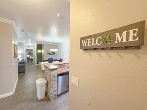 Uma cozinha moderna com parede de detalhes em pedra, lava-louças embutida e um letreiro 'WELCOME' com folhagem.
