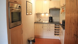 A compact kitchen with stainless steel appliances, wooden cabinets, and a tiled backsplash. - Rhododendrons Rd501 Center & Telecabine 4 Pers (Chatel)