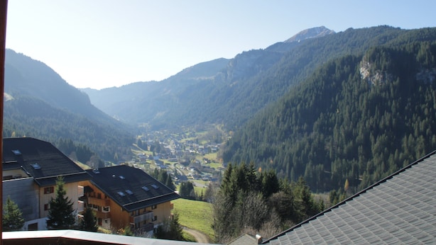 Ein Bergdorf mit Blick auf ein Tal und bewaldete Hügel.