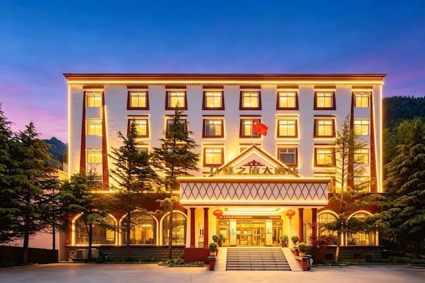 Un hôtel à plusieurs étages, doté d’une entrée imposante, de grandes fenêtres et d’un drapeau.