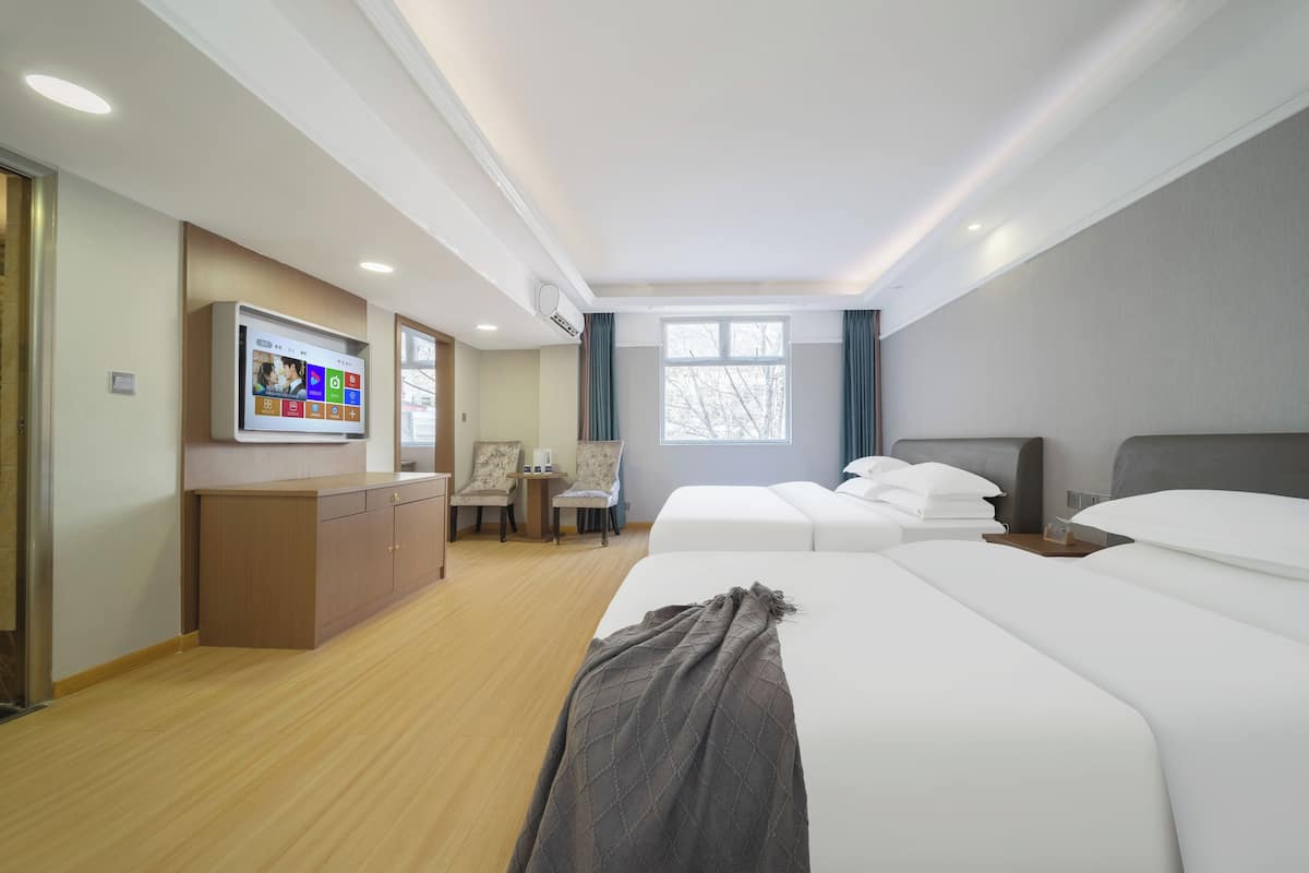 Ein Hotelzimmer mit Bett, Nachttischen, Fernseher, Schreibtisch und Fenster.
