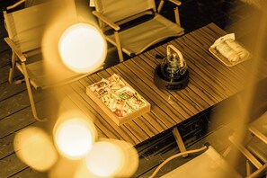 Une table en bois sur laquelle se trouvent un plateau de nourriture, une bouteille et un petit objet décoratif.