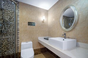 Une salle de bain équipée d’une douche, de toilettes, d’un lavabo et d’un miroir.