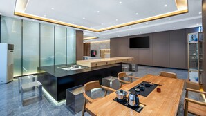 A modern kitchen with a central island, a dining area with a wooden table and chairs, and a flat-screen TV mounted on the wall.
