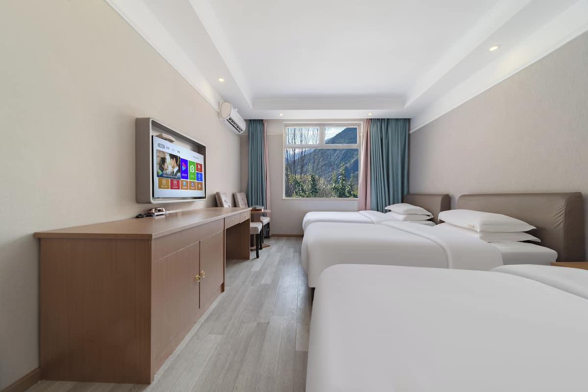Ein Hotelzimmer mit Bett, Schreibtisch, Fernseher und Fenster mit Bergblick.