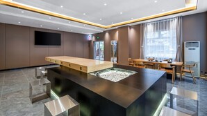 A modern hotel lobby with a reception desk, seating area, and a large window.