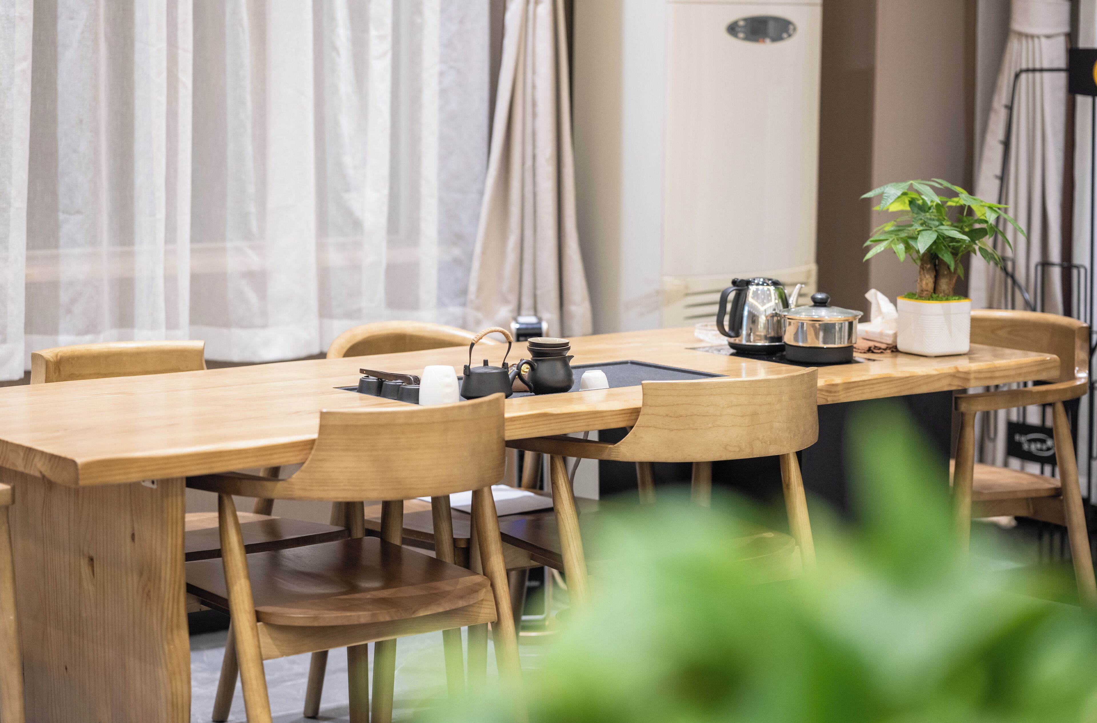 A wooden dining table with chairs, a potted plant, and kitchenware.