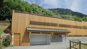 A building with a wooden facade, a garage door, and a stone wall. - Gentianes Gna17 Cosy & Mountain 4 Pers (Chatel)
