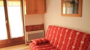 A red sofa with heart patterns, a wooden cabinet, and a radiator. - Gentianes Gna17 Cosy & Mountain 4 Pers (Chatel)