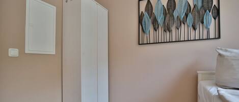 A bedroom with a wardrobe, a bed, and a wall-mounted artwork.