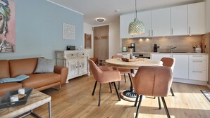 Un salon moderne avec un canapé en cuir marron, un meuble blanc et un coin repas comprenant une table ronde et des chaises.
