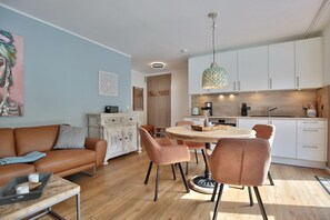 Ein modernes Wohnzimmer mit einer braunen Ledersofa, einem weißen Schrank und einem Essbereich mit einem runden Tisch und Stühlen.