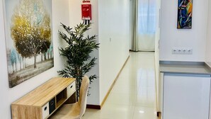 Un ingresso moderno con una panca in legno, una pianta in vaso, un quadro e un angolo cottura con frigorifero bianco.