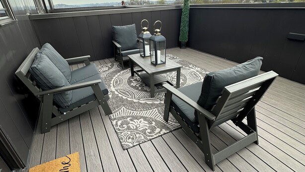 A rooftop deck with two lounge chairs, a small table, and two lanterns.