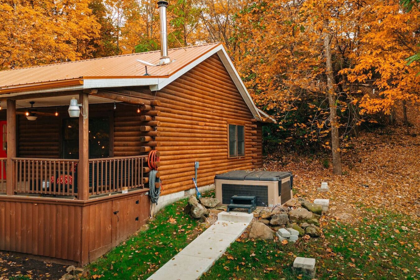 A log cabin with a deck, a hot tub, and a chimney.
