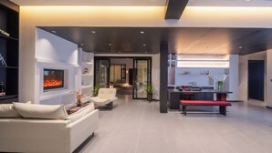 Una sala de estar moderna con chimenea, un sofá, un banco y un comedor con mesa y sillas.