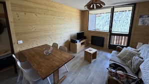 A cozy wooden cabin interior with a dining table, chairs, a TV, and a sofa. - Hameau DES 4 Saisons Hsc113 Mountain & View 6 Pers (Chatel)