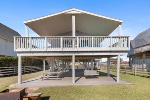 A covered outdoor deck with picnic tables and a railing.