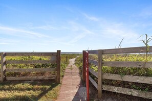 A wooden pathway leading to a beach with a clear sky.