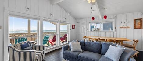 A spacious living room with a large sofa, striped armchair, and a dining table.