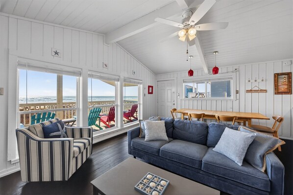 A spacious living room with a large sofa, striped armchair, and a dining table.