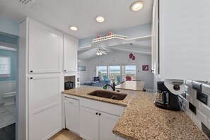 A modern kitchen with white cabinetry, granite countertops, and a built-in dishwasher.