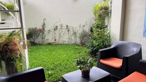 Eine Terrasse mit Gartenmöbeln, einer kleinen Rasenfläche und Topfpflanzen.