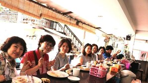 A group of people dining at a table in a room with a staircase and a balcony in the background. - Vientianestar  (Vientiane)