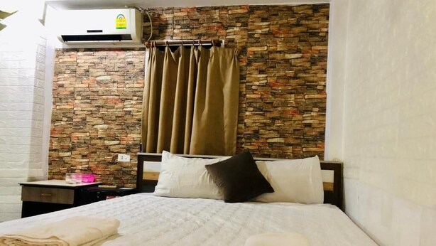 A hotel room with a bed, a nightstand, a wall-mounted air conditioner, and a curtain. - Vientianestar  (Vientiane)