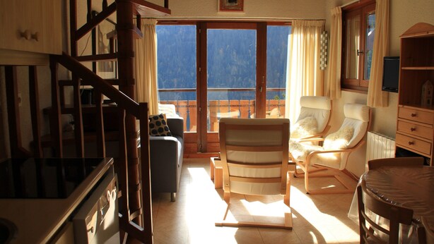 A spacious living room with a wooden staircase, a balcony with a view, and a dining area with a table and chairs. - Barbessine Bbb11 SUN & Chair Lift 5 Pers (Chatel)