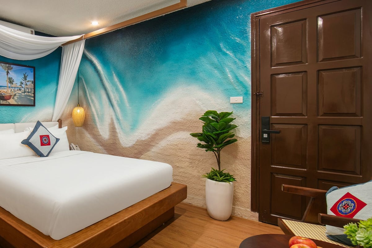 A bedroom with a bed, a nightstand, a potted plant, and a door.