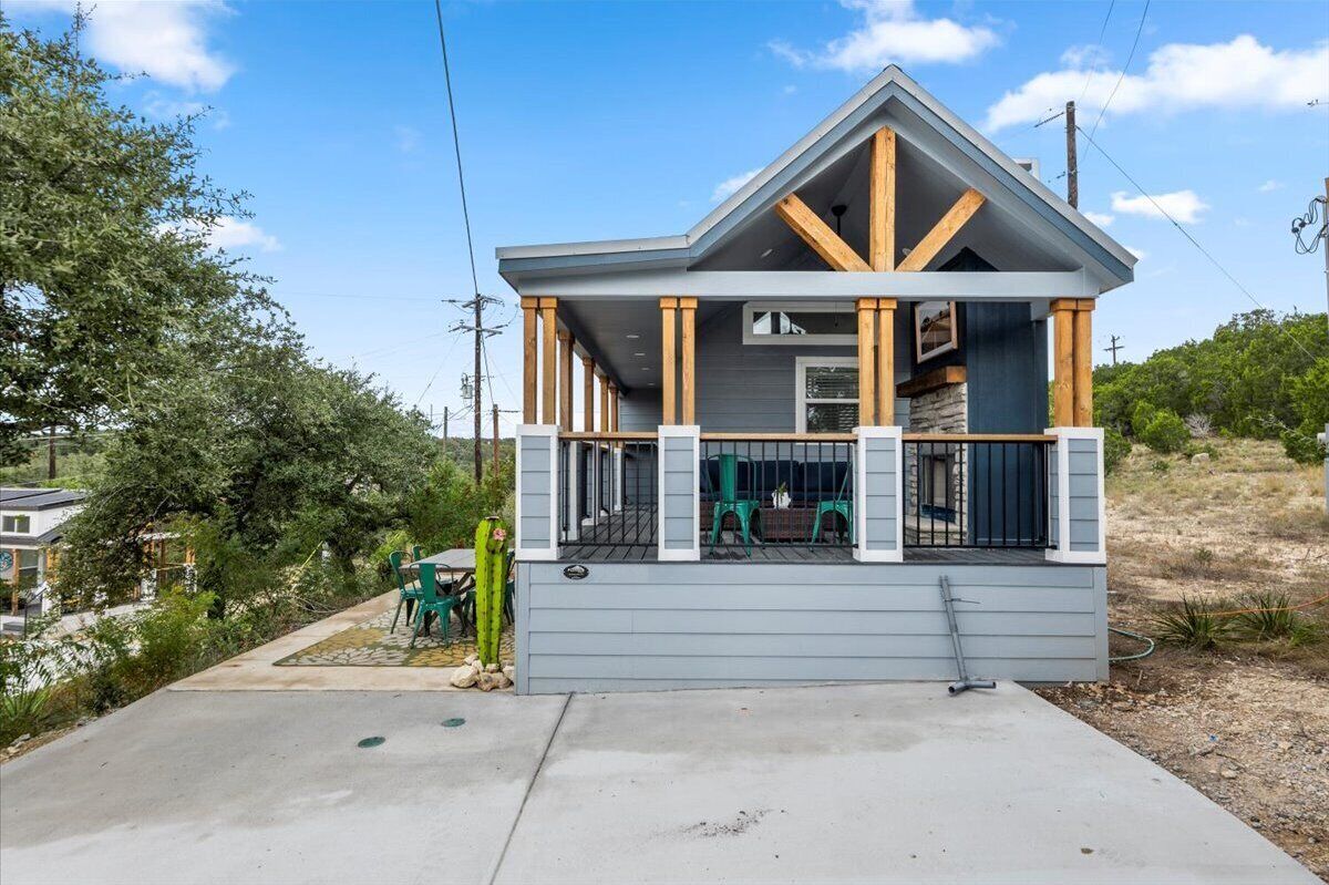 A modern house with a covered porch, wooden beams, and a grey exterior.