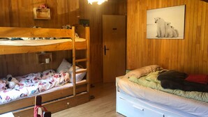 A room with wooden walls, a bunk bed, a single bed, a wooden ladder, a door, and a framed picture on the wall. - Chalet Ours Blanc ORS Nature & Quiet 6 Pers (Chatel)