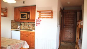 A compact kitchen with wooden cabinets, a microwave, and a tiled backsplash. - Alpage Aga13 View & Mountain 3 Pers (Chatel)