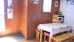 A small wooden room with a table and benches, a microwave, and a door with a window. - Alpage Aga13 View & Mountain 3 Pers (Chatel)