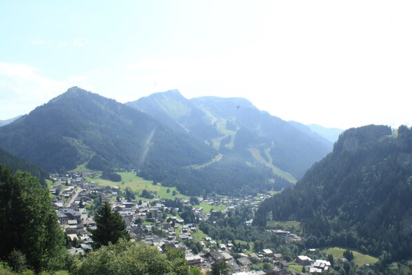 A mountain town with houses and buildings nestled in a valley, surrounded by forested mountains. - Alpage Aga13 View & Mountain 3 Pers (Chatel)