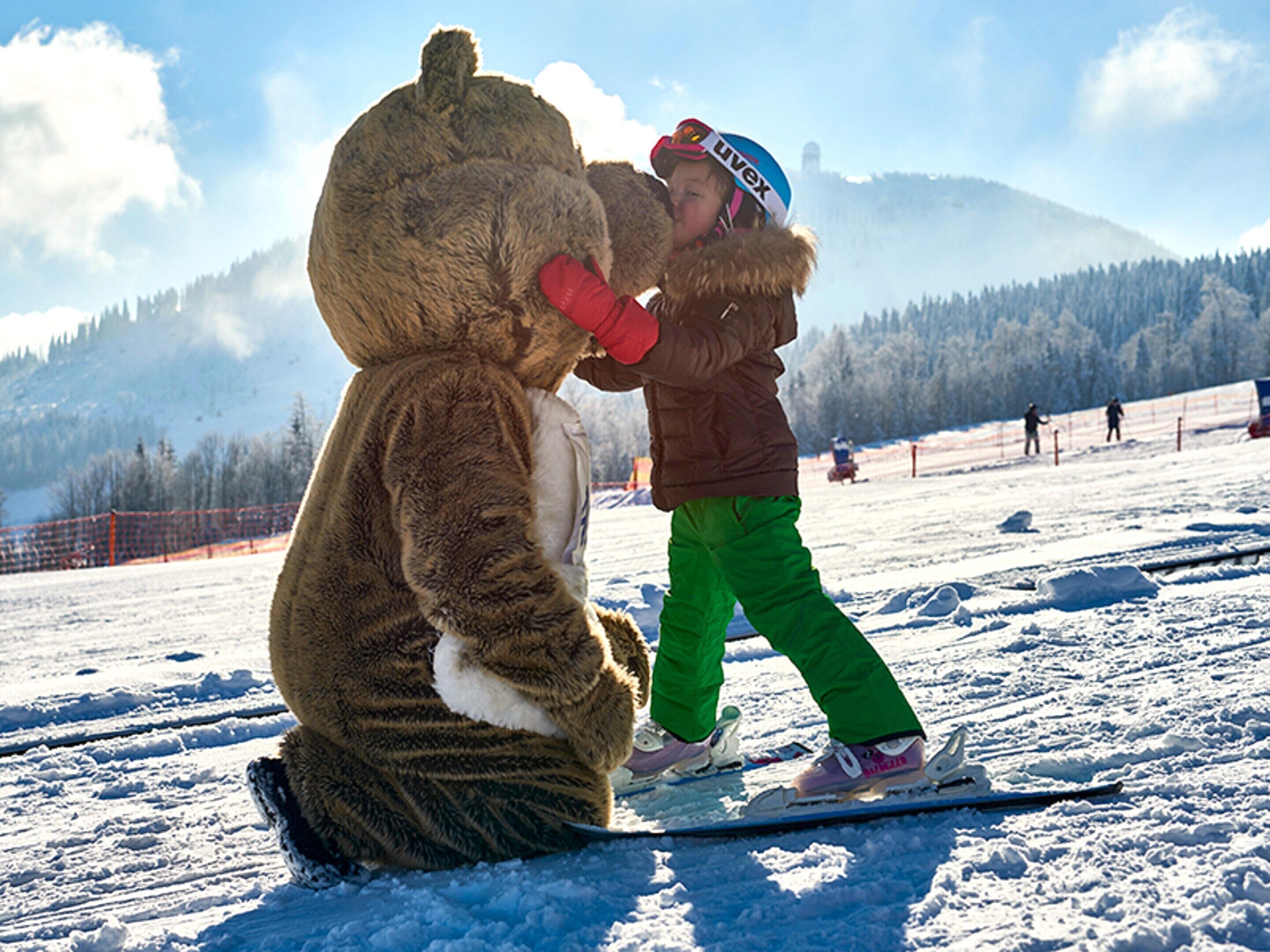 A person in a bear costume on skis on a snowy slope.