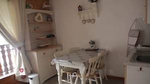 A small kitchen with a dining table, chairs, and a white cabinet. - Orchidee OD5 Nature & Telecabine 4 Pers (Chatel)