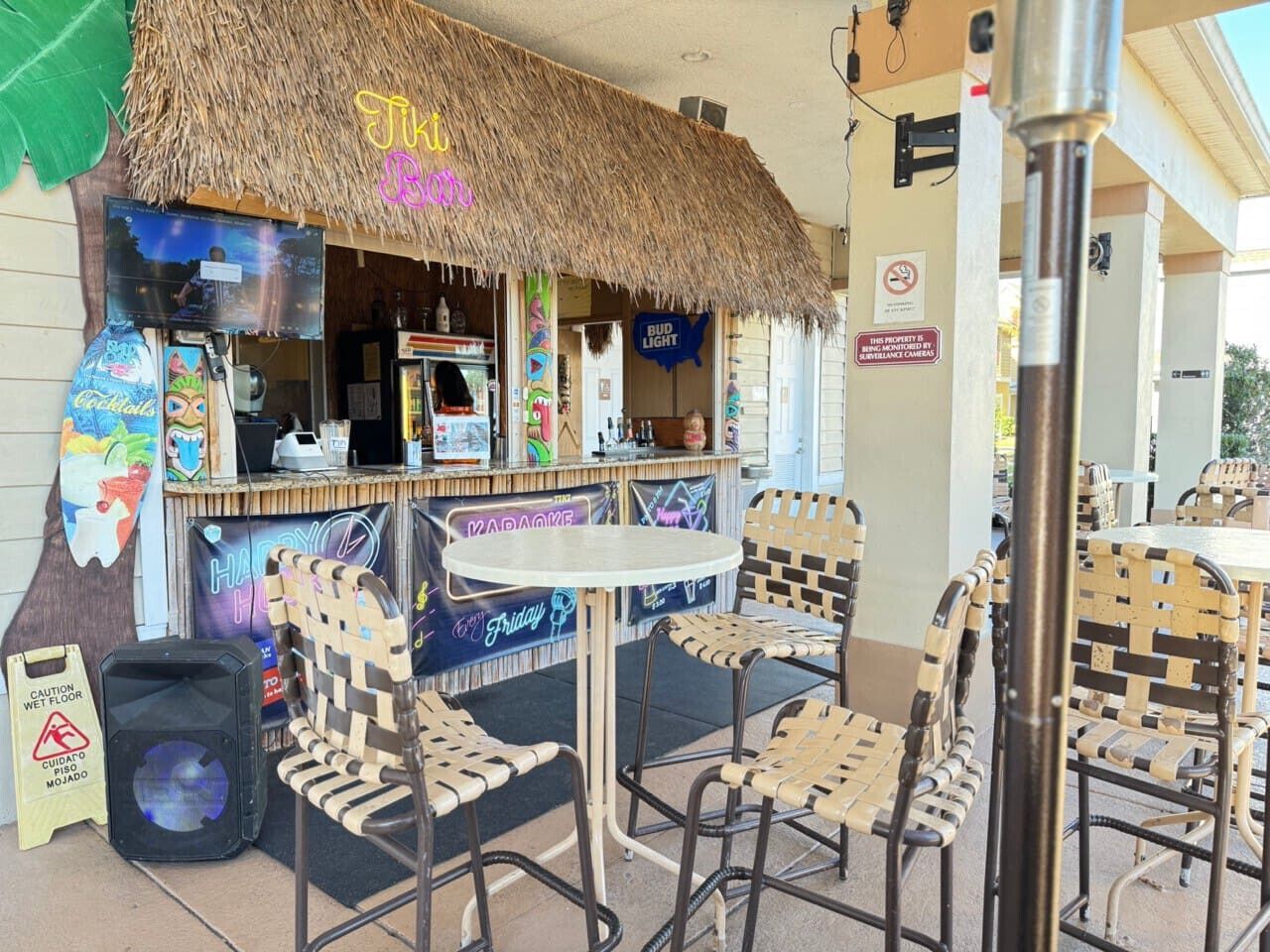 Ett utomhusområde med bar, försett med ett halmtak, en tiki-bar och sittplatser med flätade stolar.