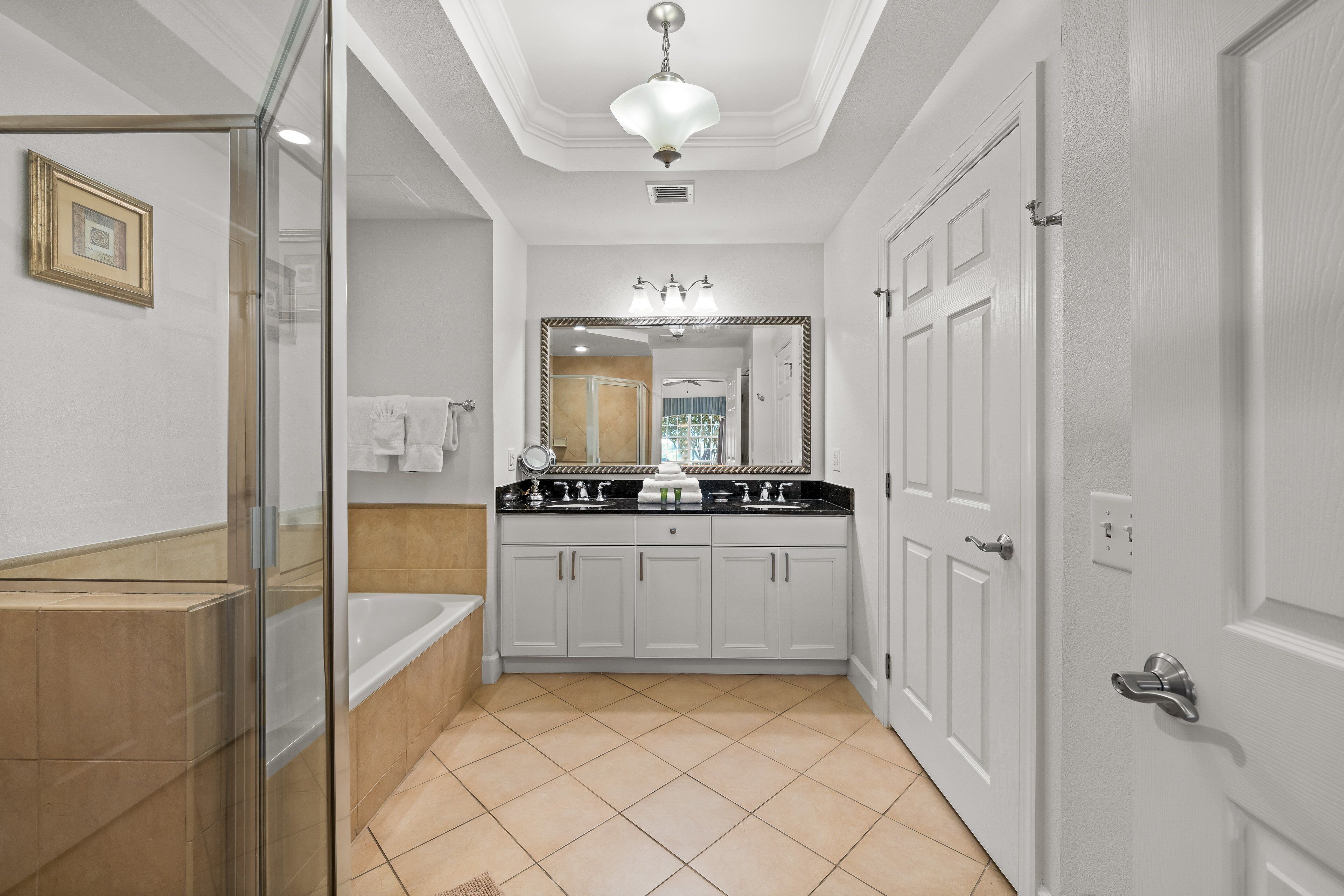 A modern bathroom with a glass shower enclosure, a double sink vanity, and a large mirror.