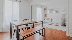 Ein modernes Wohnzimmer mit einem Holzessttisch, Stühlen, einem Glastisch und einem weißen Sofa.