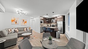 Un apartamento moderno con sala de estar, comedor, cocina y un ventanal grande.
