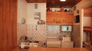 Una cocina compacta con armarios de madera, microondas, estufa y pileta.