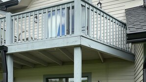 Une maison à deux étages dotée d’un balcon, d’un porche abrité et d’un petit espace extérieur aménagé pour s’asseoir.