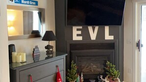 Un salon doté d’une cheminée, d’un téléviseur fixé au-dessus et d’une enseigne au-dessus de la cheminée sur laquelle on peut lire « EVL ».