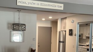 Une pièce comprenant un lit, une table à manger avec des chaises, un réfrigérateur et un coin cuisine visible à travers une porte ouverte.