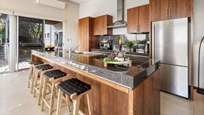 Una cocina moderna con una isla central, electrodomésticos de acero inoxidable, armarios de madera y un amplio ventanal.