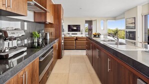 Una cocina moderna con armarios de madera oscura, encimera negra y electrodomésticos de acero inoxidable.