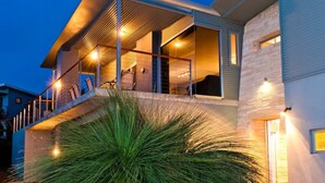 Una casa moderna con balcón, escalera e interior bien iluminado.